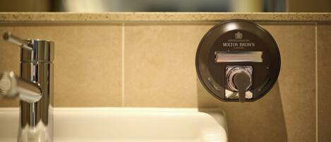 A bathroom sink with a modern faucet and a wall-mounted hand and body wash dispenser.