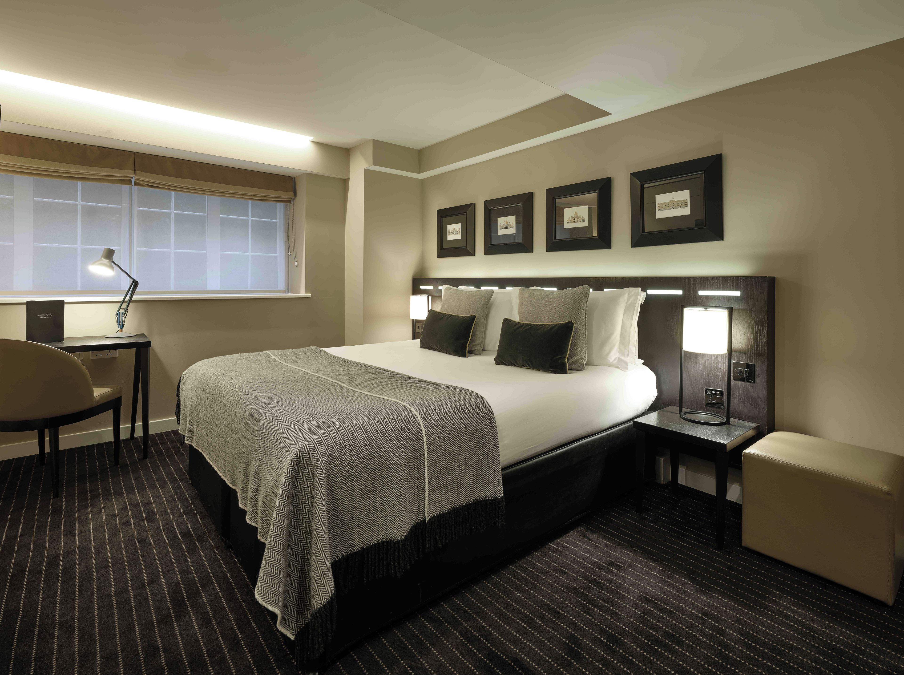 Une chambre d’hôtel équipée d’un lit, d’un bureau, d’une chaise et d’une fenêtre avec des stores.