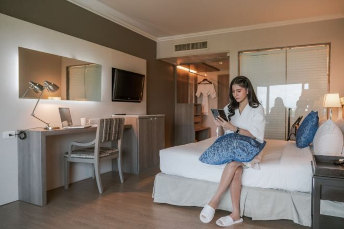 Une chambre d’hôtel moderne équipée d’un lit, d’un bureau avec une chaise, d’un téléviseur fixé au mur et d’une armoire.
