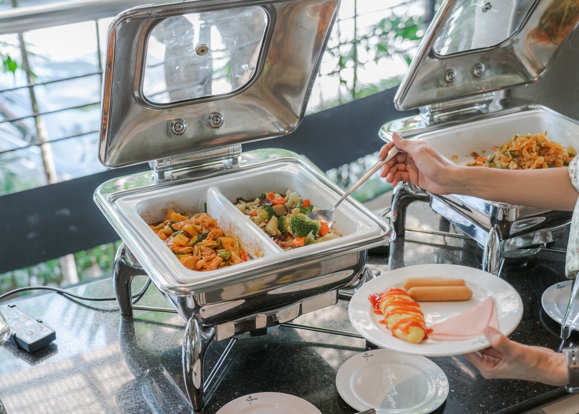 Un buffet avec deux présentoirs ouverts, dont l’un propose une variété de plats et l’autre, une assiette de nourriture et un hot-dog.