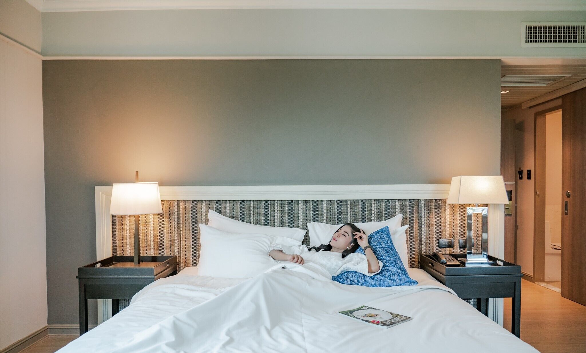 Quarto de hotel com uma cama grande, duas mesas de cabeceira e cabeceira com design estampado.