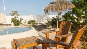 A poolside area with wooden chairs and a thatched umbrella. - Menzelcaja (Aghir)