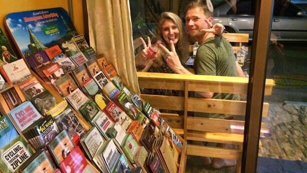 A bookstore with a variety of travel and adventure books displayed on shelves and tables. - The Living Place 2 - Hostel (Chiang Mai)