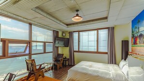 Una habitación de hotel con un ventanal grande, una cama, un escritorio y una silla.