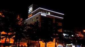 Un hotel con un cartel llamativo que dice 'HOTEL' en la fachada, un cartel en la azotea y un anuncio que indica 'ABIERTO'.