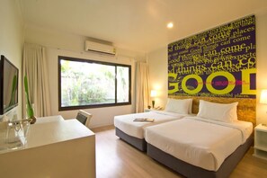 Une chambre d’hôtel avec deux lits, un bureau et une grande fenêtre.