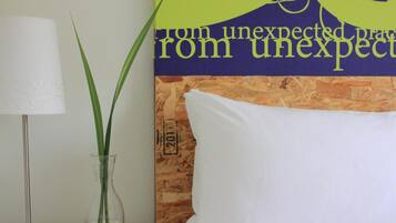 A room with a white pillow, a clear vase with green plants, and a wall with a poster.