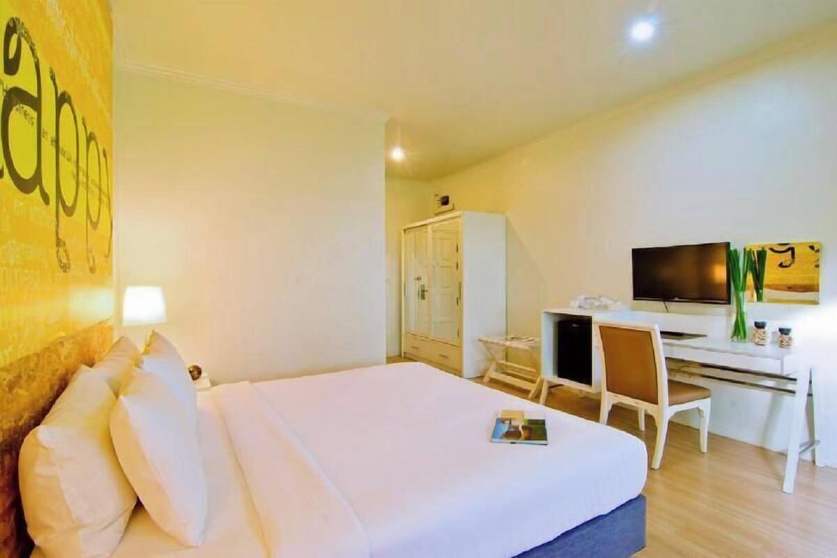 A hotel room with a bed, a desk, a TV, and a wardrobe.