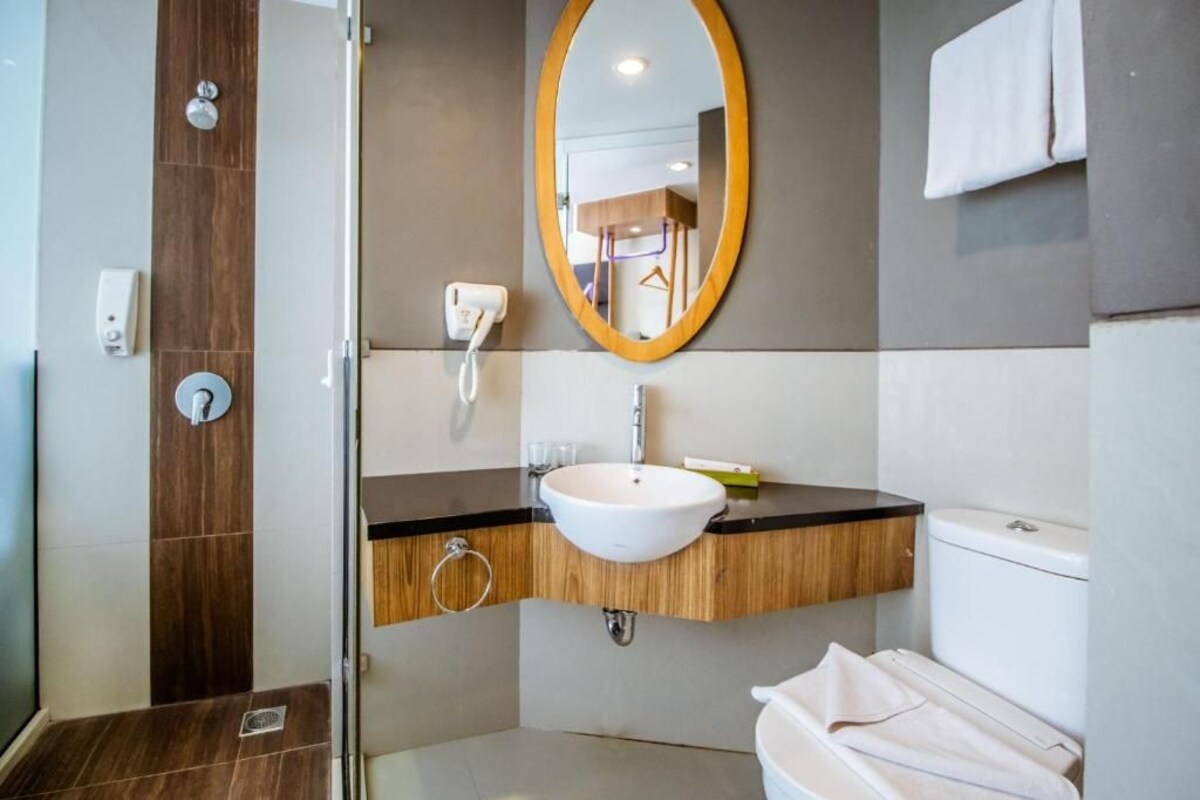 A modern bathroom with a wooden vanity, a white sink, a mirror, and a toilet.
