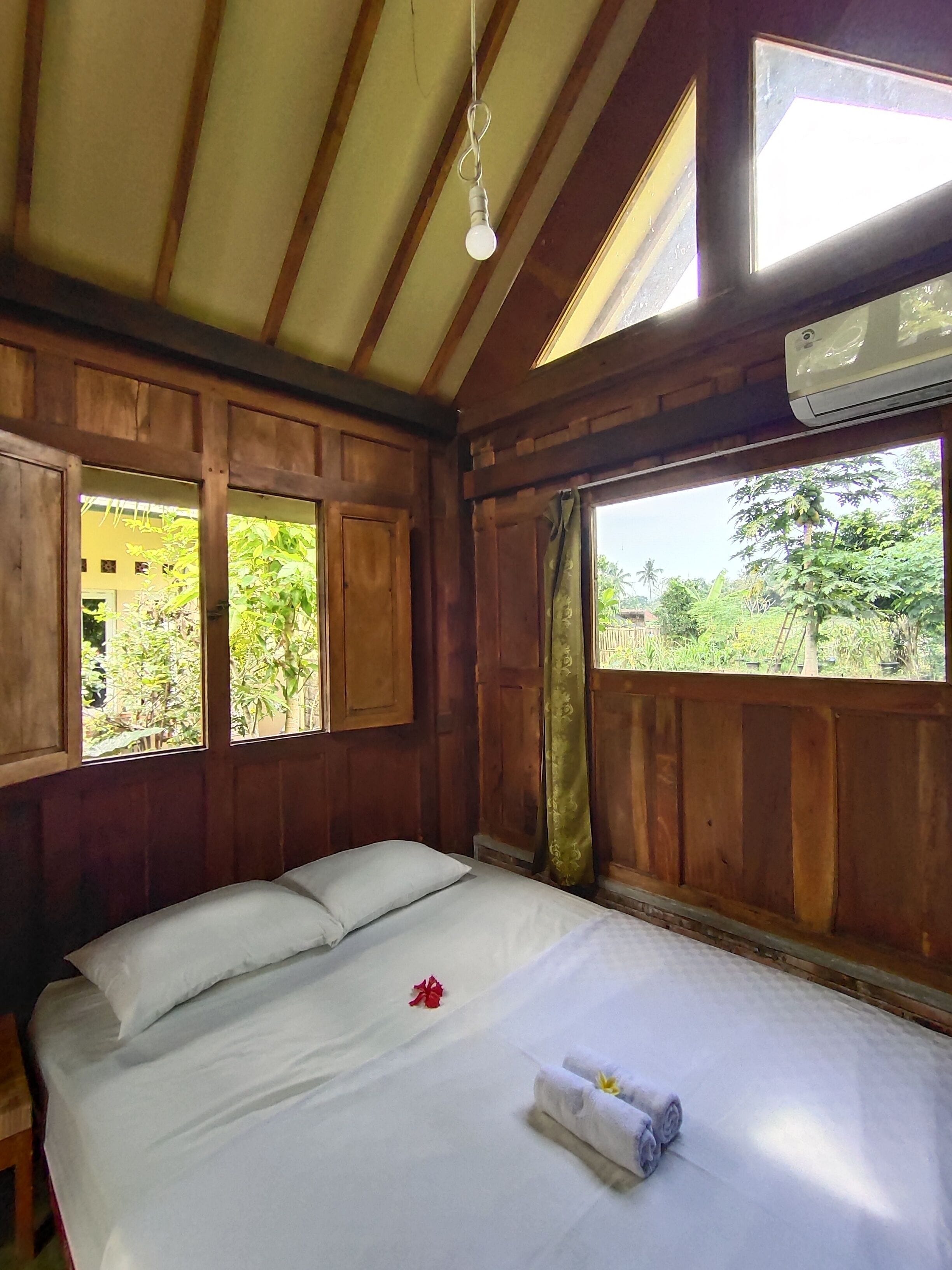 Une pièce en bois avec un lit, une fenêtre et un appareil de climatisation.