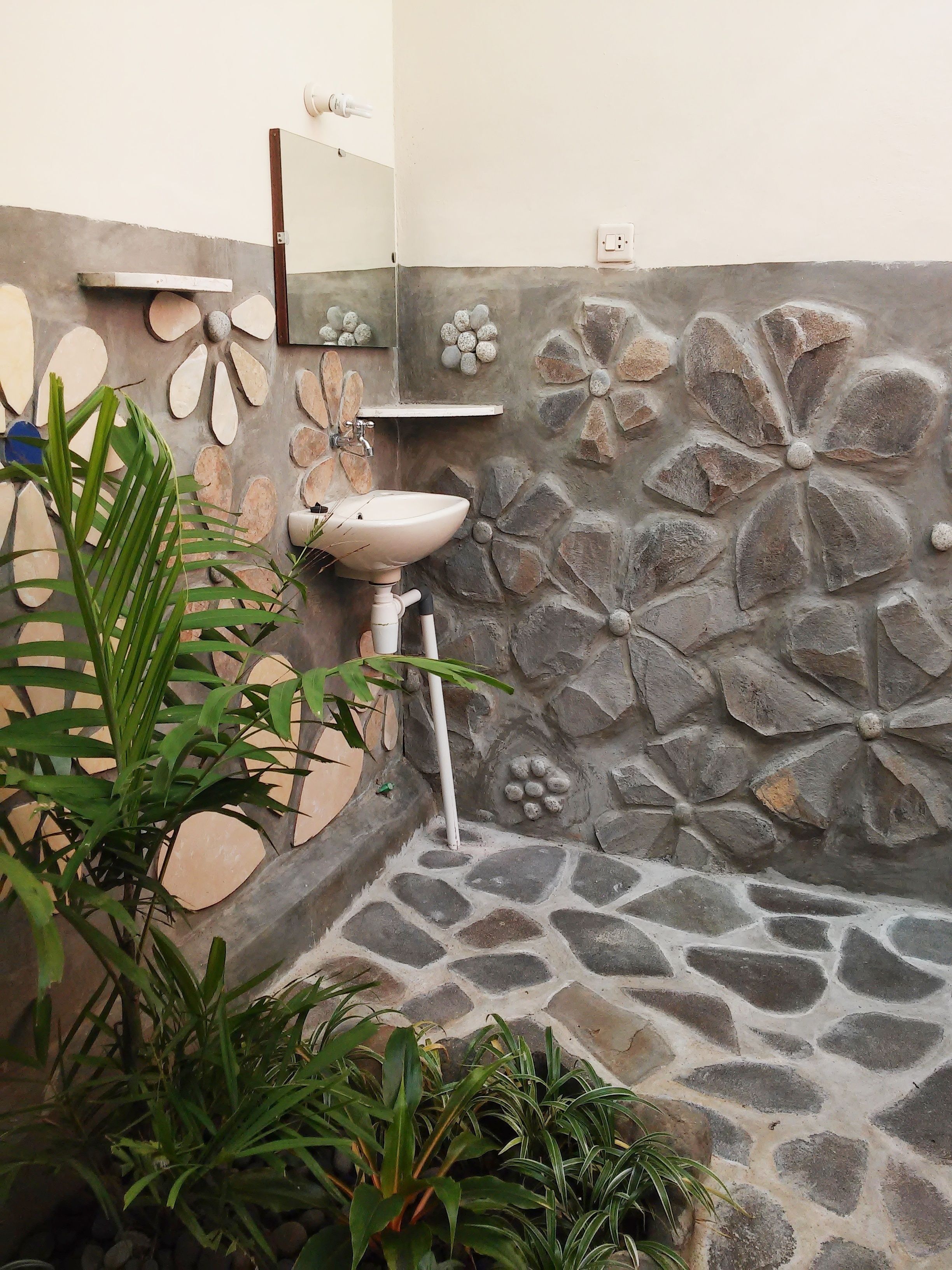 A bathroom with a stone wall, a sink, and a mirror.