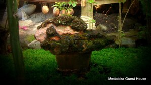 A traditional wooden house with a porch, surrounded by lush greenery and a small garden. - Mettaloka Guest House and Art Space (Borobudur)