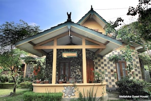 A guest house with a checkered facade, a stone wall, and a signboard. - Mettaloka Guest House and Art Space (Borobudur)