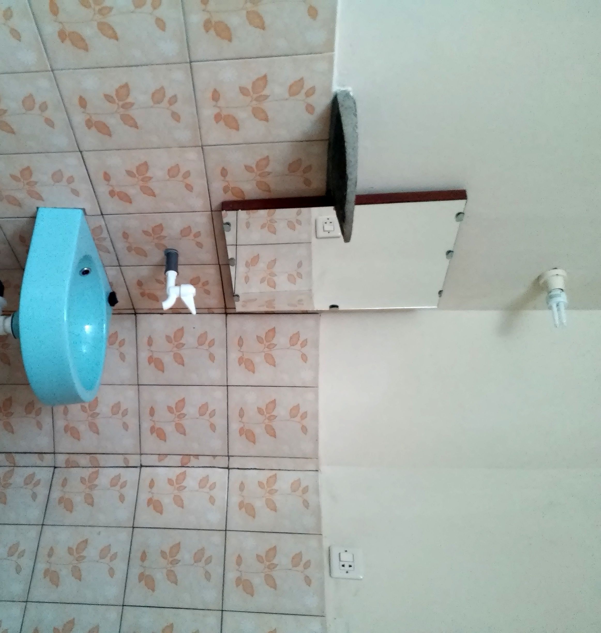 A bathroom with a blue sink, a white toilet, and a wall-mounted faucet.