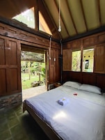Una habitación de madera con cama, ventana y puerta que da a un espacio exterior.