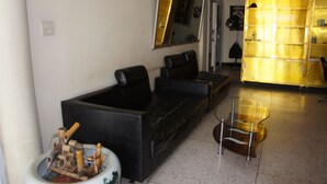 Un salon moderne avec un canapé noir, une table basse en verre et un meuble jaune.