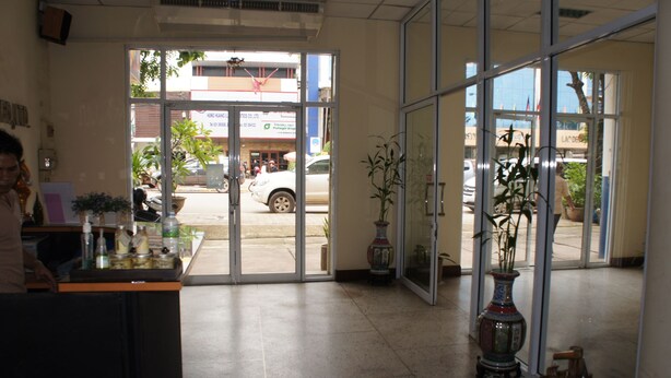 Un espace d’accueil avec un comptoir, des plantes en pot et une vue sur la rue.