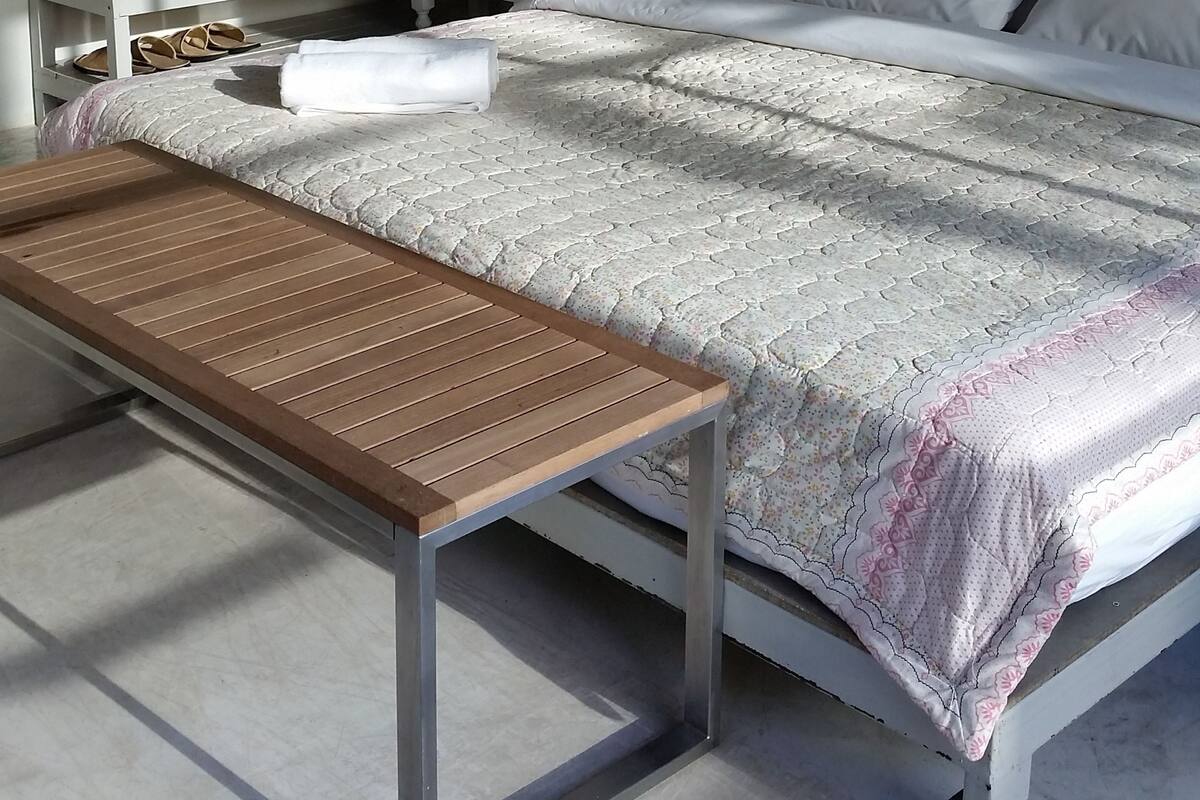 A neatly arranged bedroom with a bed, bedside tables, a wooden bench, and wall decorations.