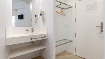 Un baño moderno con un tocador blanco, un espejo, zona de ducha y una puerta con un mapa.