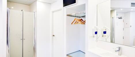 A modern bathroom with a glass shower enclosure, a vanity with a mirror, and a hanging coat rack.