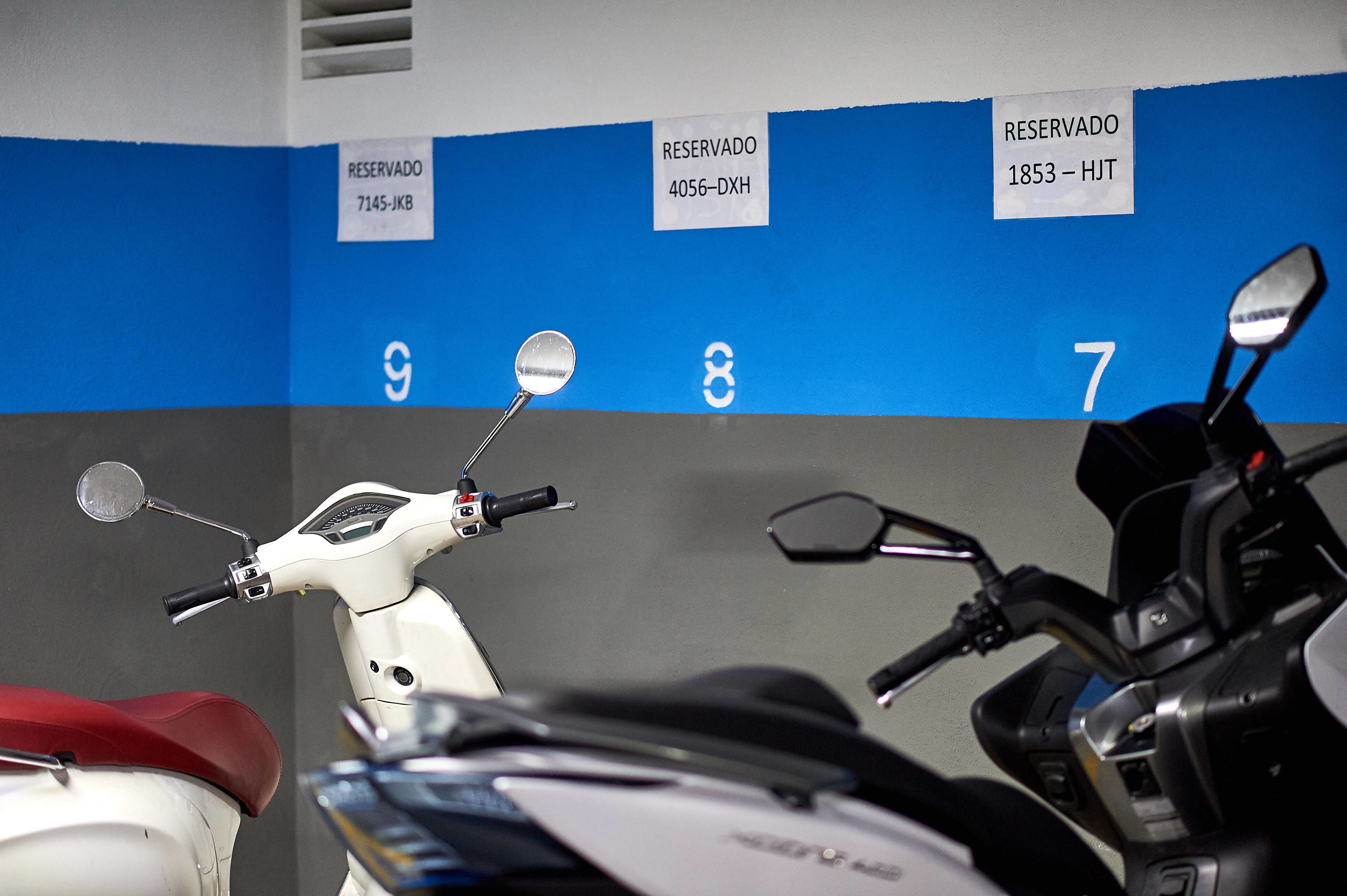 Un espacio de estacionamiento con scooters y motocicletas, cada uno identificado con un cartel de reserva.