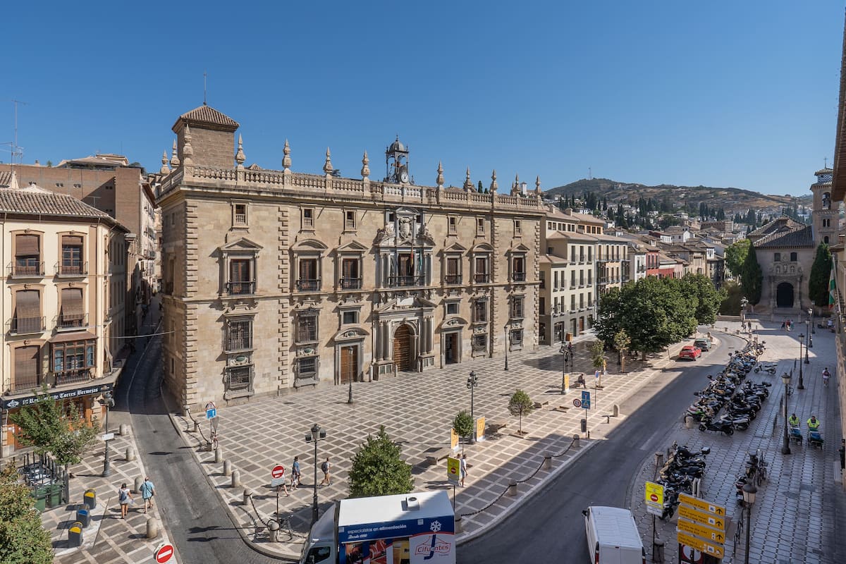A large historic building with a central courtyard, surrounded by other buildings.
