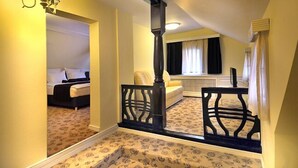 Quarto com cama, escrivaninha e cadeira. Há uma janela com cortinas e radiador.