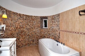 A bathroom with a mosaic tile wall, a freestanding bathtub, and a small window. - Vila Economat (Sinaia)