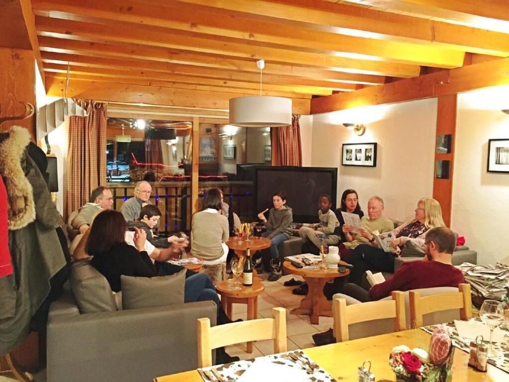 A cozy indoor setting with wooden beams, a television, and people seated around tables.
