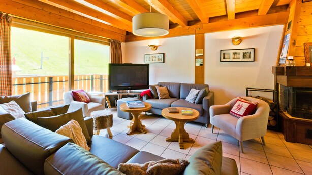 Una sala de estar acogedora con un conjunto de sofá, dos mesas redondas de centro, una chimenea y un televisor.