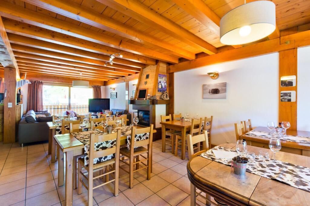 A spacious dining area with wooden tables and chairs, a television, and a fireplace.