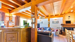 Un interior de cabaña acogedor con una barra de madera, un sofá, una chimenea y una zona de comedor.