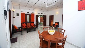 A dining area with a round wooden table and chairs, a basket of fruit, and a ceiling fan. - Summer Dew Villa (Unawatuna)