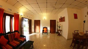 A spacious living area with a sofa, a dining table with chairs, and a chair with a cushion. - Summer Dew Villa (Unawatuna)