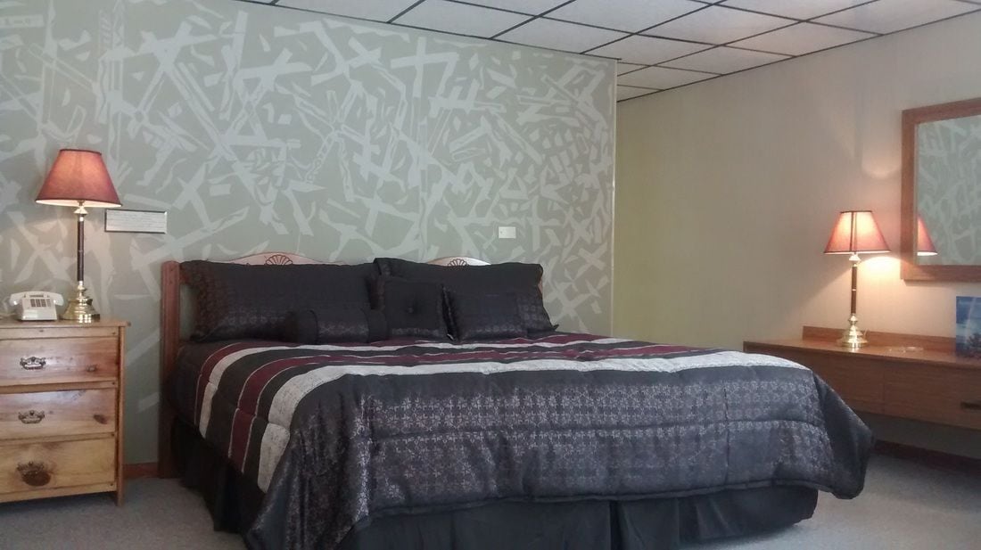 A bedroom with a bed, two bedside lamps, a nightstand with a telephone, and a dresser.