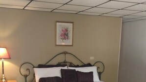 Une chambre d’hôtel standard, avec un lit simple, une table de chevet, une lampe et un tableau encadré au mur.
