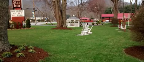 A grassy area with a gazebo, trees, and a sign for 'Five Star Inn' with 'CREEK SIDE UNITS' and 'VACANCY' information.