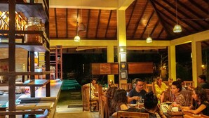 Un restaurante con mobiliario de madera y luces colgantes.