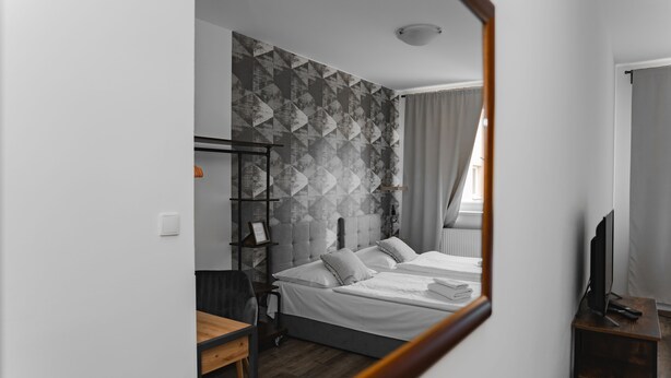 A modern hotel room with a bed, a desk, a TV, and a wardrobe. - Hotel Arko (Prague)