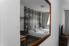 A modern hotel room with a bed, a desk, a TV, and a wardrobe. - Hotel Arko (Prague)