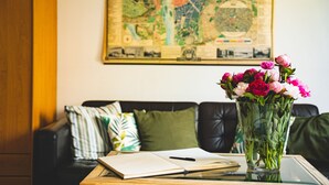 A living room with a coffee table, a book, a pen, and a vase of flowers. - Hotel Arko (Prague)