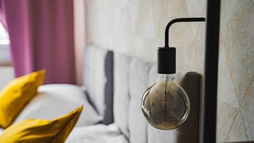 A modern room with a hanging light fixture, a sofa with cushions, and a marble wall.