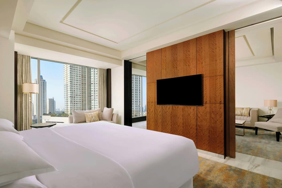 Une chambre d’hôtel avec un grand lit, un téléviseur à écran plat, un canapé et une vue sur le paysage urbain.