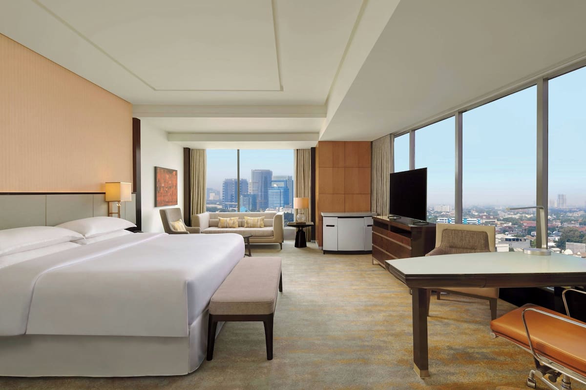 Une chambre d’hôtel avec un grand lit, un bureau, une chaise, une télévision et une vue sur le paysage urbain.