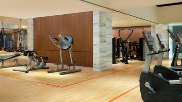 Un gimnasio moderno con diversos equipos de ejercicio, incluyendo cintas de correr, bicicletas estáticas y máquinas de pesas.