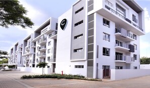 A modern multi-story residential building with balconies, a prominent 'C' logo, and a gated entrance. - The Capital on Bath (Johannesburg)