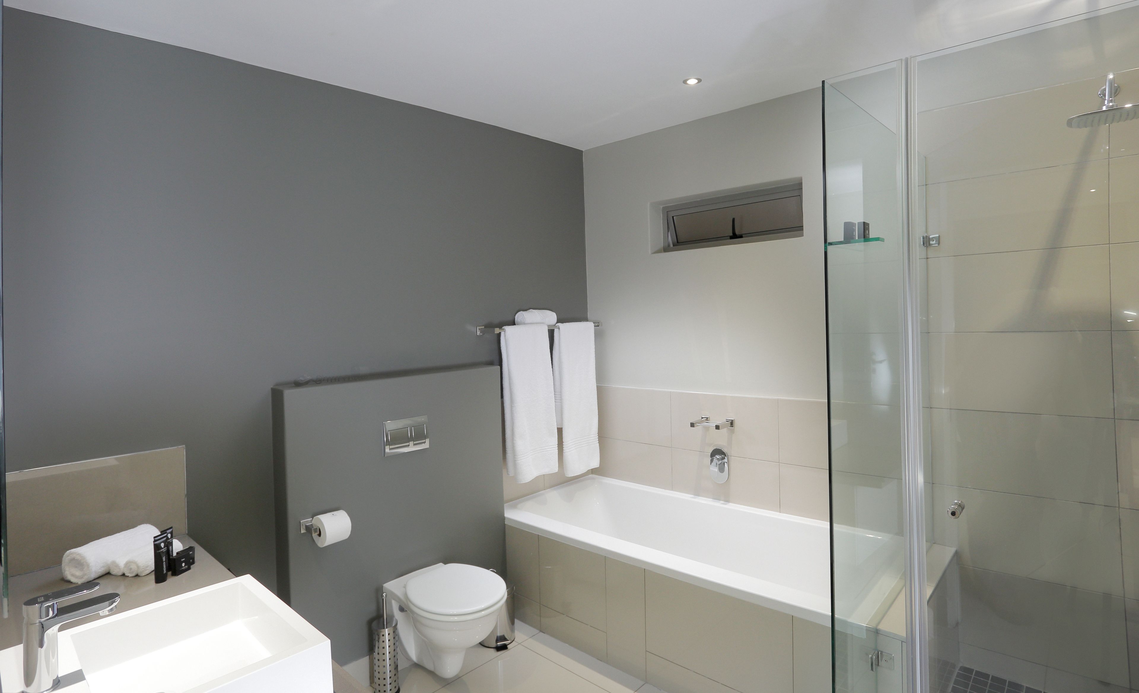 Un bany modern amb banyera, vàter i cabina de dutxa de vidre.