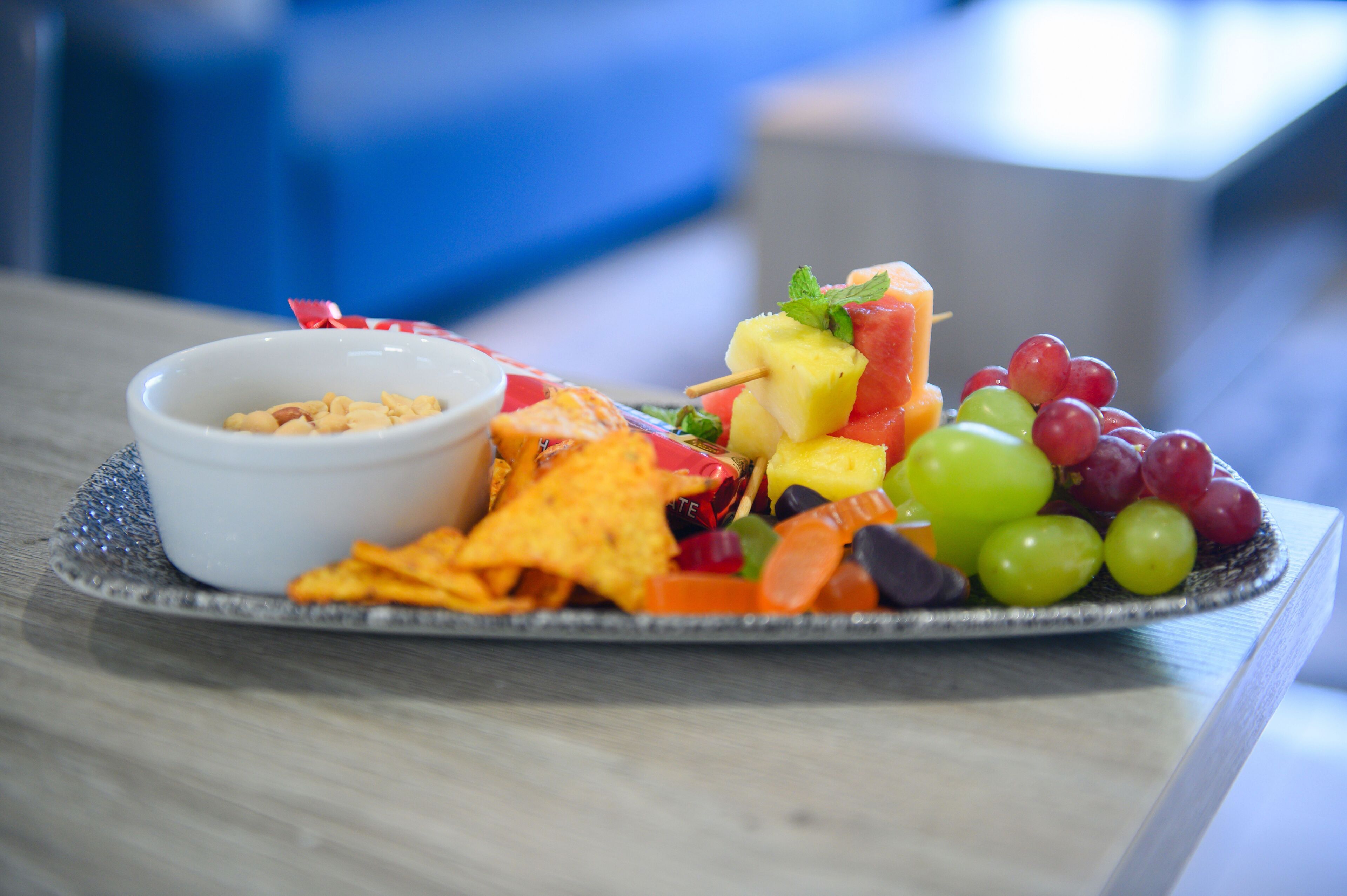 Ein Teller mit verschiedenen Snacks, darunter Chips, Obst und eine kleine Schale Dip.
