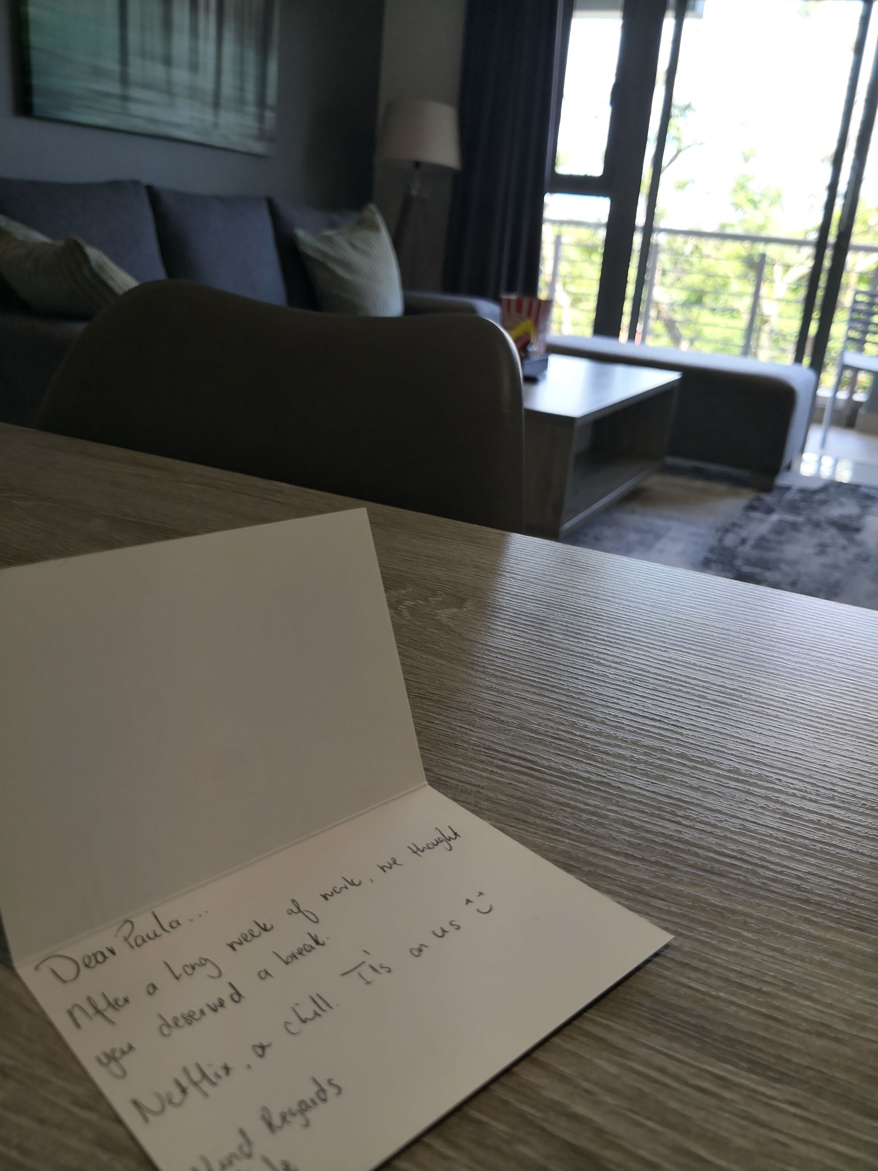 Una nota escrita a mano sobre una mesa en una sala de estar con vista al exterior.