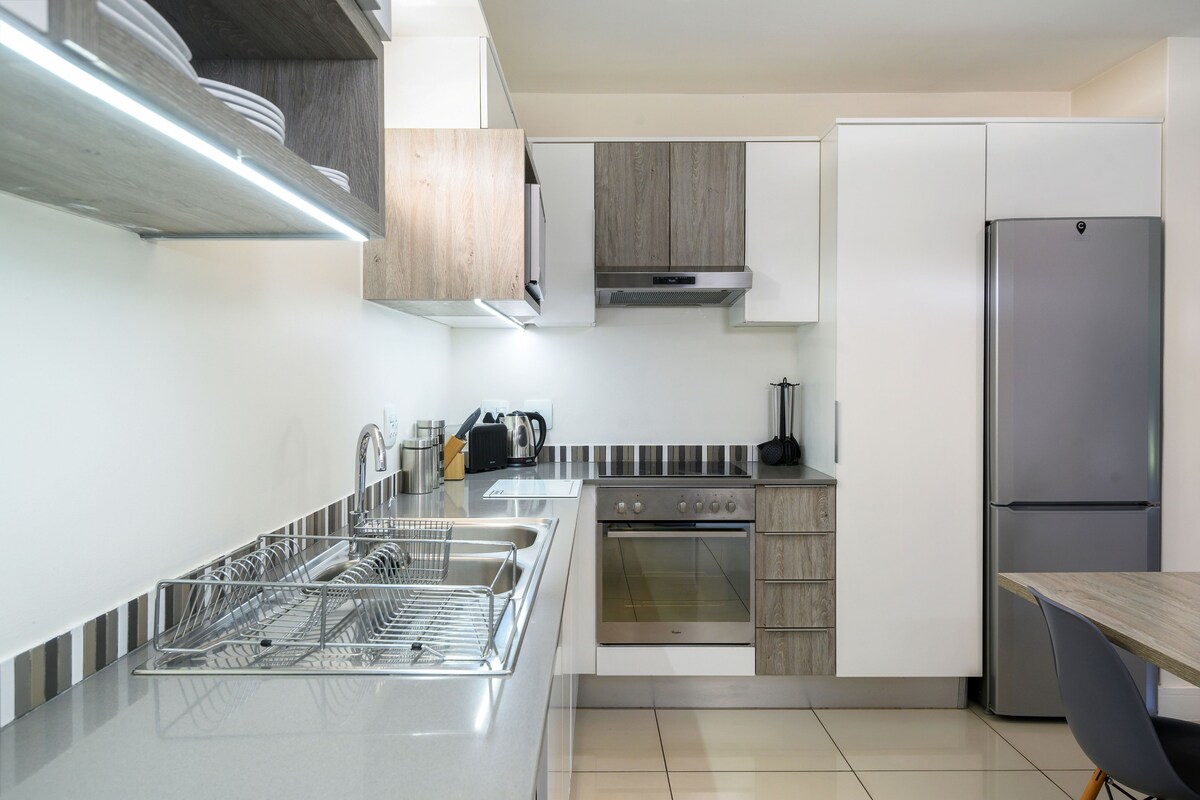 A modern kitchen with stainless steel appliances, wooden cabinets, and a built-in dishwasher.